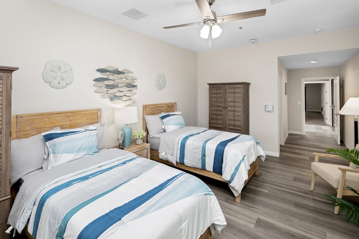 A cozy bedroom with two twin beds, striped bedding, and a ceiling fan.