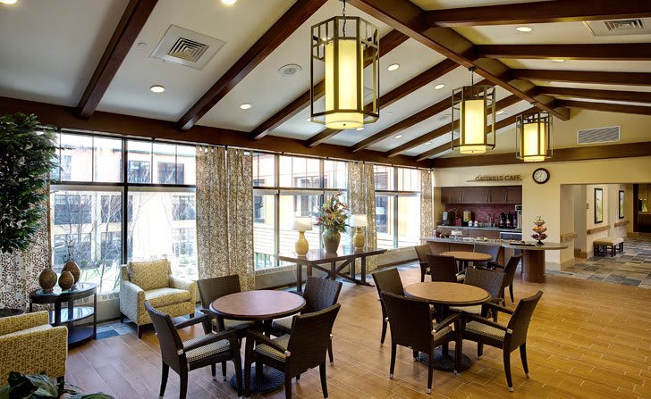 A cozy dining area with round tables, chairs, and elegant lighting fixtures.