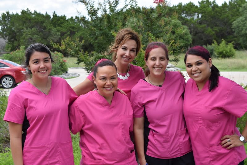 A group of women in pink uniforms posing together outdoors.