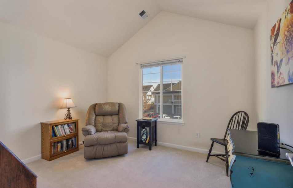 A cozy living room with a plush armchair, bookshelf, and a window letting in natural light.