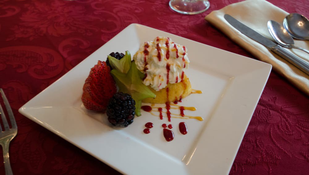 A gourmet dessert featuring a selection of fresh fruits and whipped cream, elegantly plated.