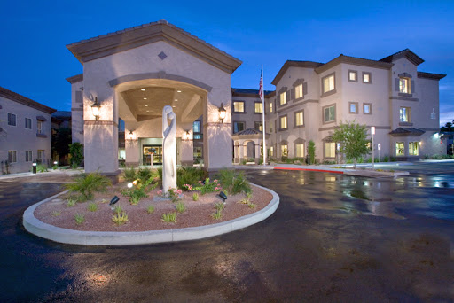 A beautifully designed modern building entrance at night, featuring elegant lighting and landscaped surroundings.