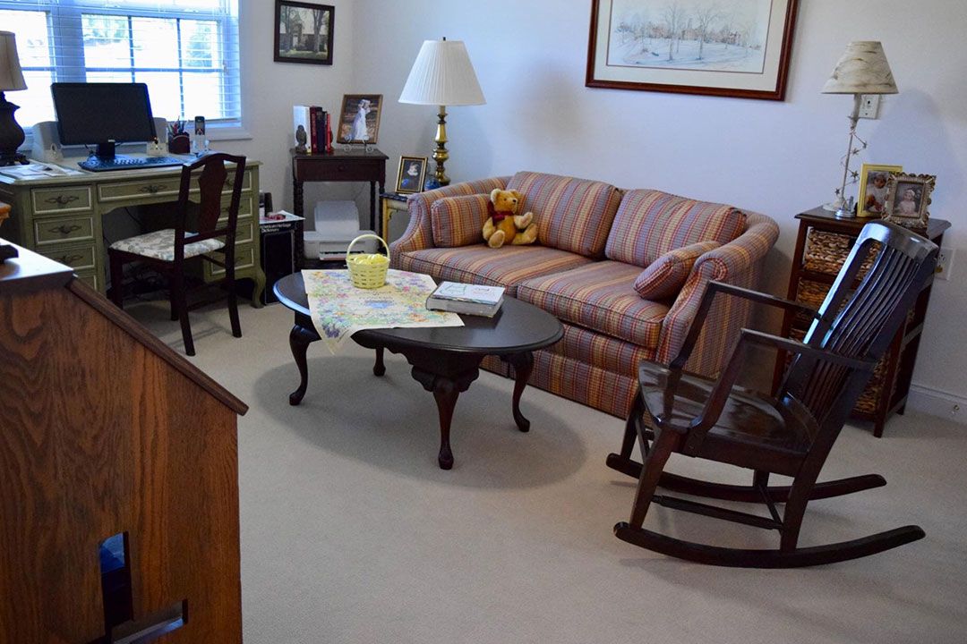A cozy living room with a striped sofa, rocking chair, and a coffee table adorned with magazines.
