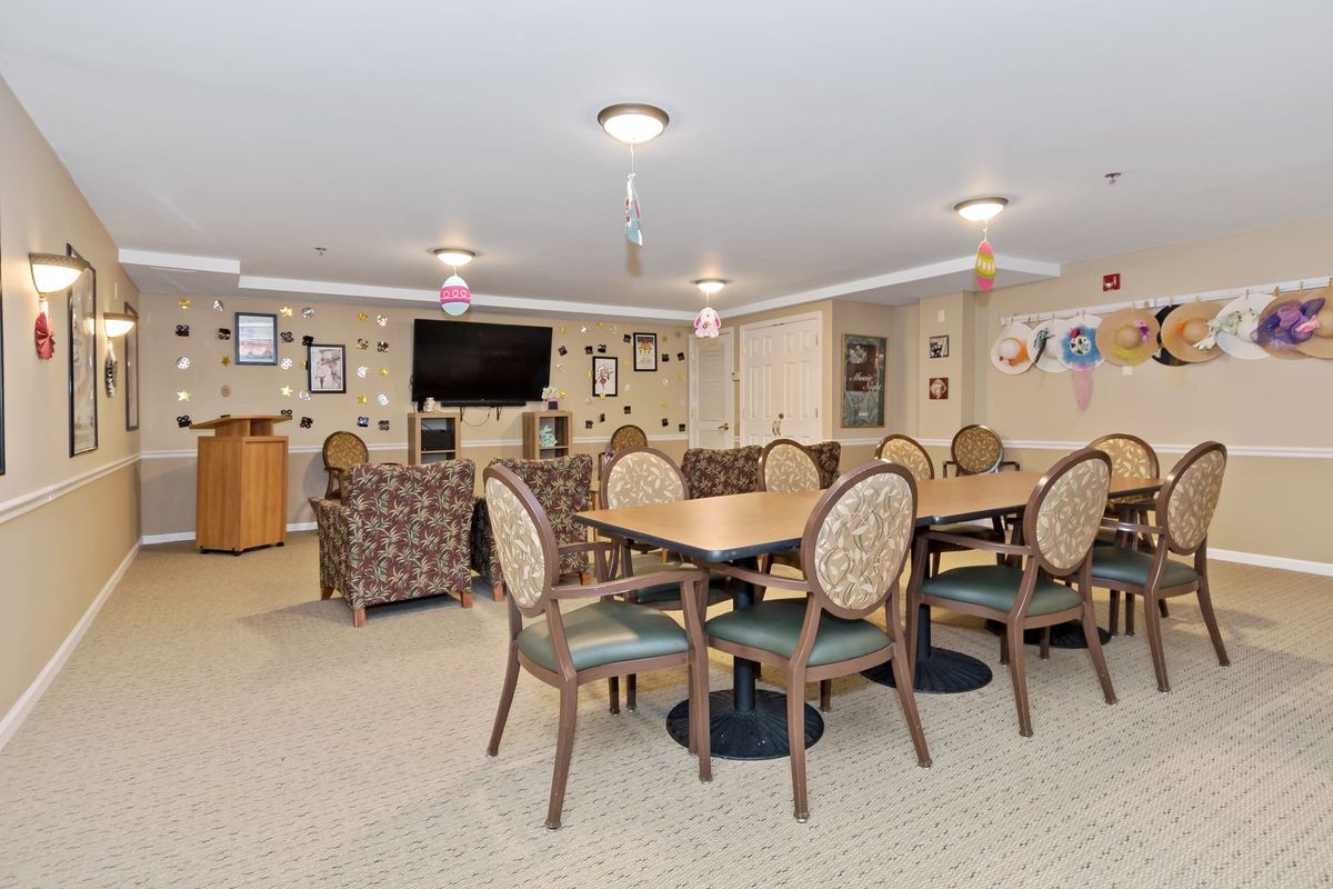 A well-furnished dining room with tables, chairs, and a television on the wall.