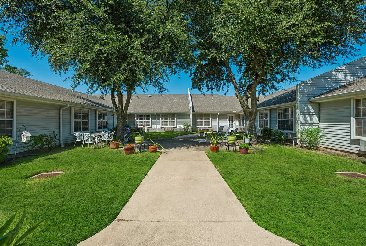 A well-maintained residential courtyard with a central sidewalk, surrounded by trees and landscaping.