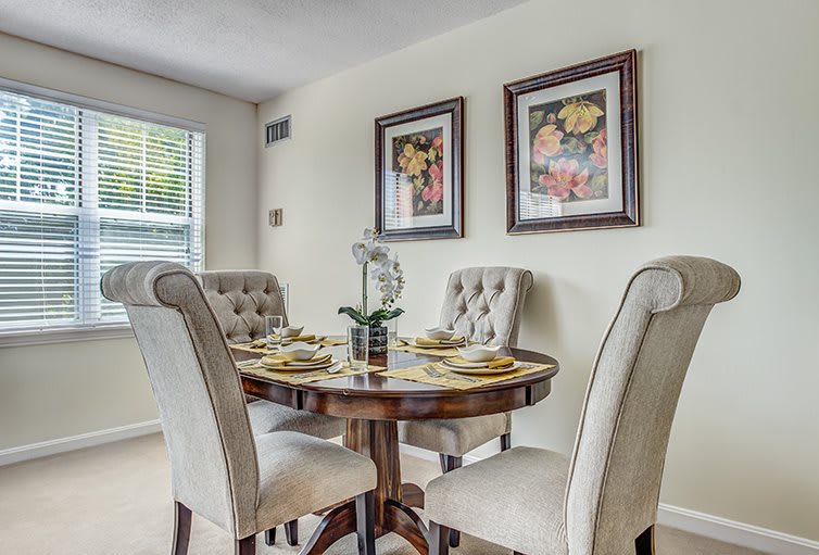 An elegant dining room with a round table and upholstered chairs, adorned with wall art and tasteful decor.