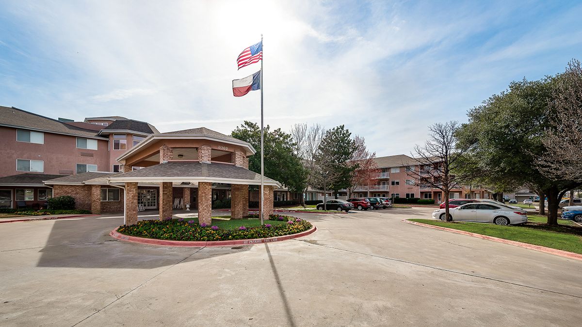 A building with flags flying above a parking lot on a clear day.
