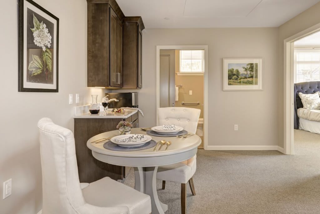A cozy dining area with a round table set for two, adjacent to a modern kitchen.