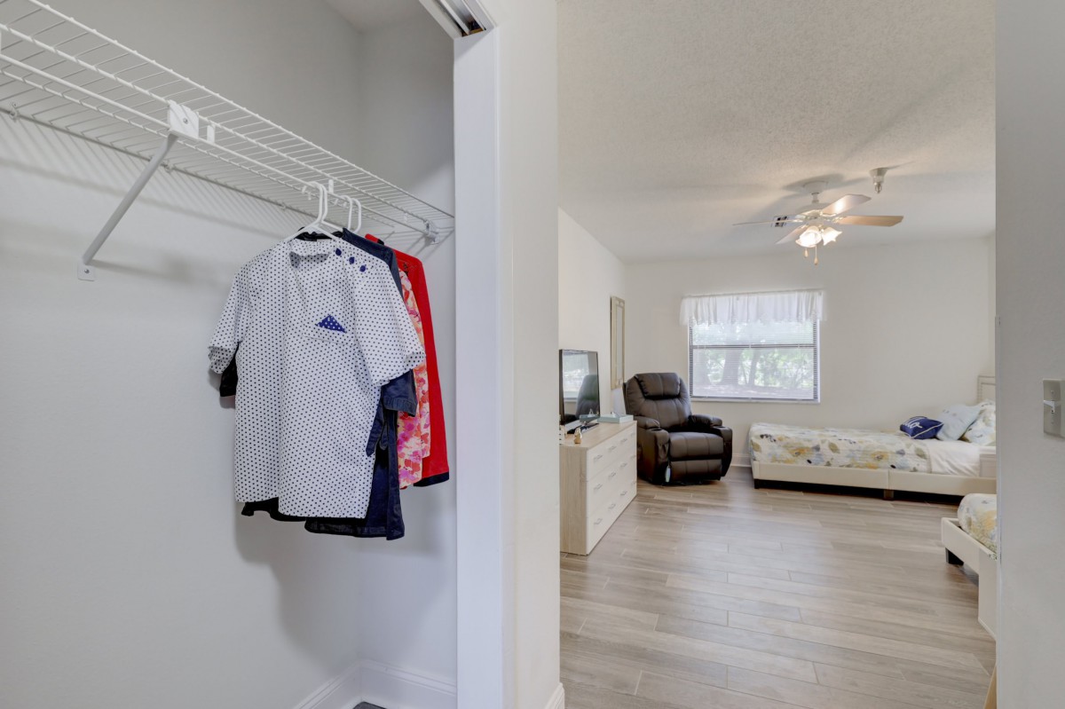 A view from the closet into a cozy living room with a sofa, recliner, and a television.
