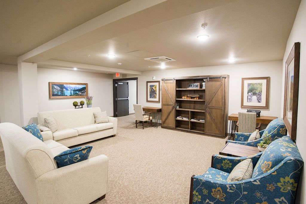 A cozy living room with sofas, shelves, and warm lighting.