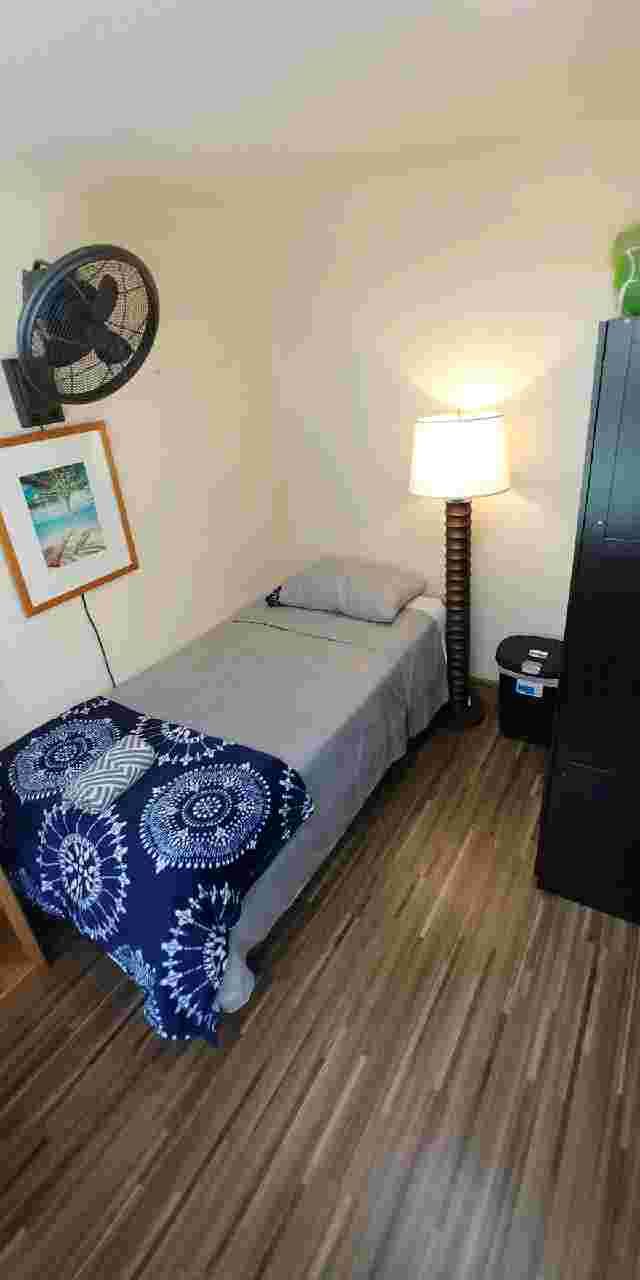 A cozy, minimalist bedroom with a single bed and a standing lamp.