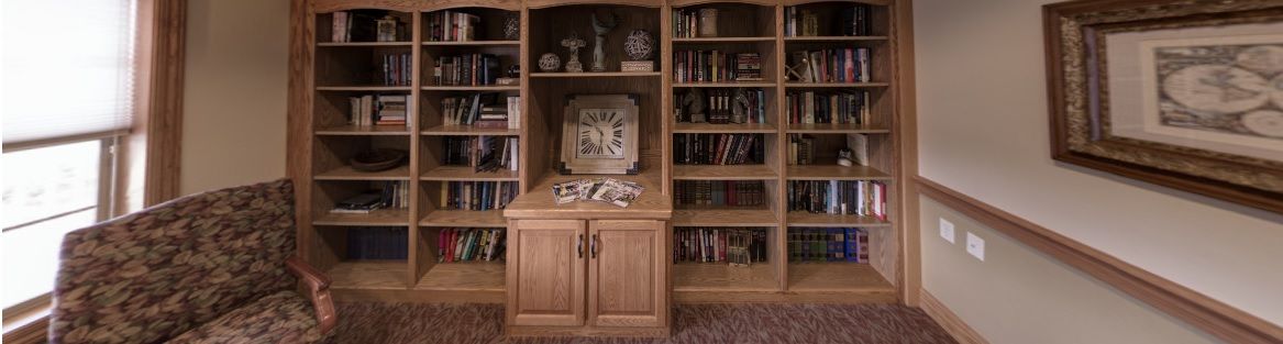 A wooden bookshelf filled with books and decorative items, featuring a central clock display.