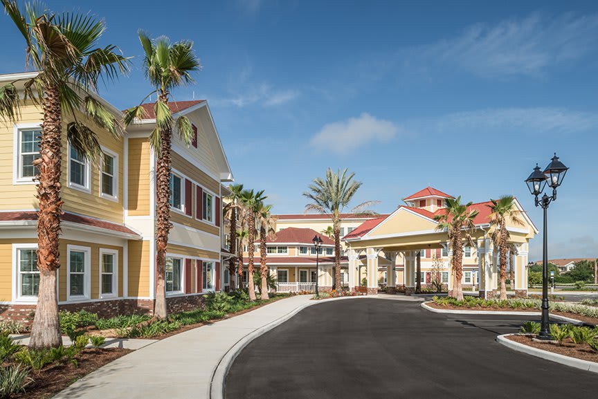 A sunny day at a residential building with palm trees lining the driveway.
