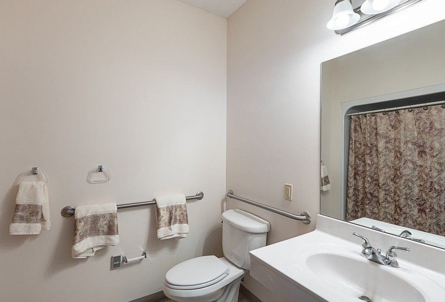 A clean and simple bathroom with a toilet, sink, and mirror.