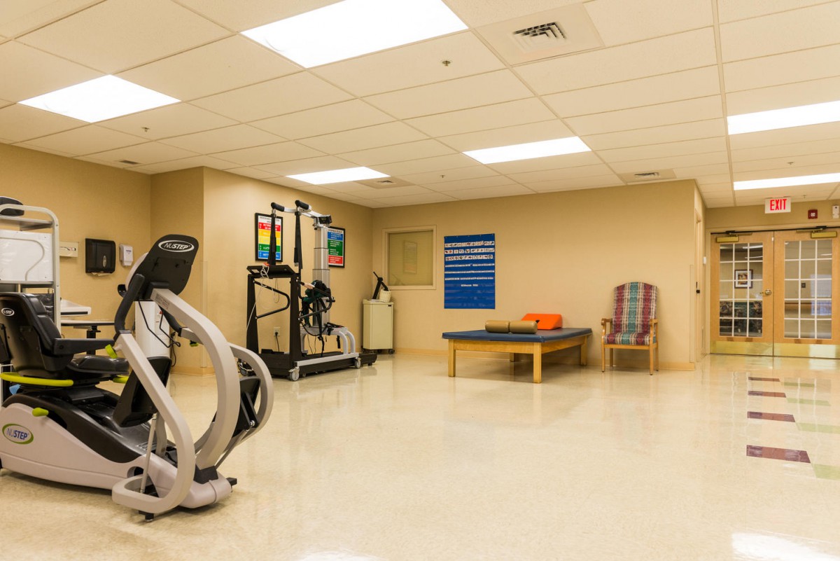 A spacious physical therapy room with gym equipment and a treatment table.
