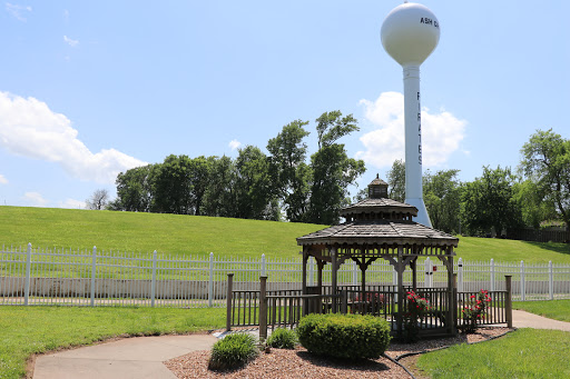 A serene outdoor scene featuring a gazebo and a water tower against a backdrop of green hills.