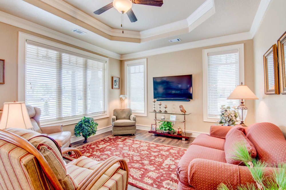 A cozy living room with elegant furniture, a large rug, and ample natural light.