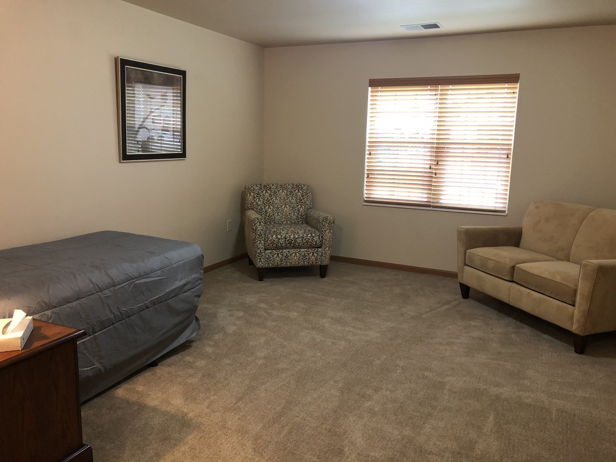 A cozy living room with armchairs, a sofa, and a carpeted floor.