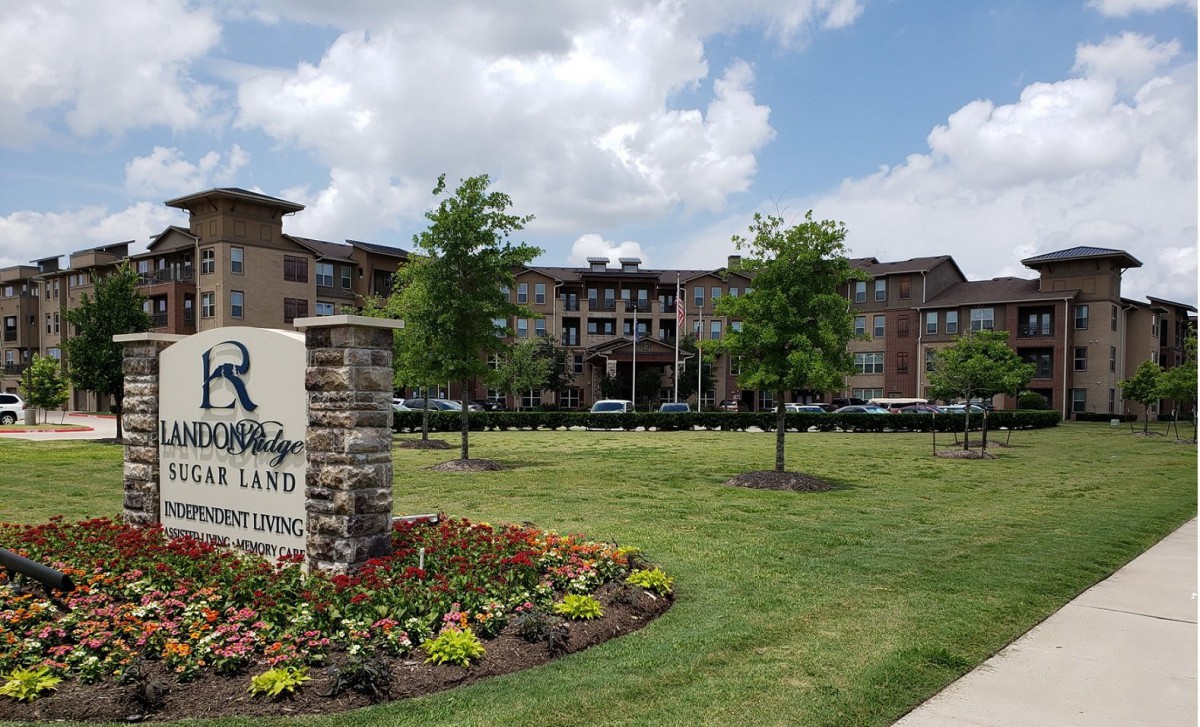 View of a modern apartment complex with landscaped surroundings and a welcoming entrance sign.