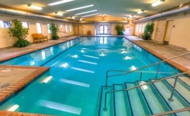 An inviting indoor swimming pool with clear blue water and ample lighting.