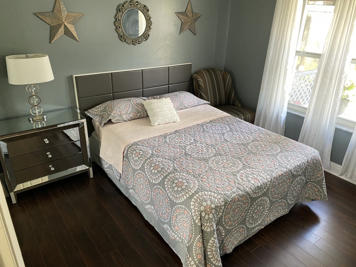 A cozy bedroom with a neatly made bed and stylish decor featuring mirrors and star-shaped wall hangings.