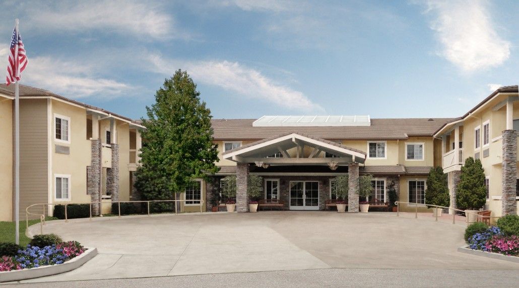 An outdoor view of a hotel entrance with a clear sky and trees.