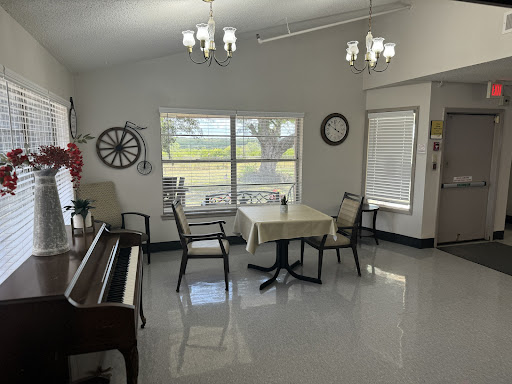 A bright and spacious dining area featuring a piano, a table with chairs, and large windows that provide a view of the outdoors.
