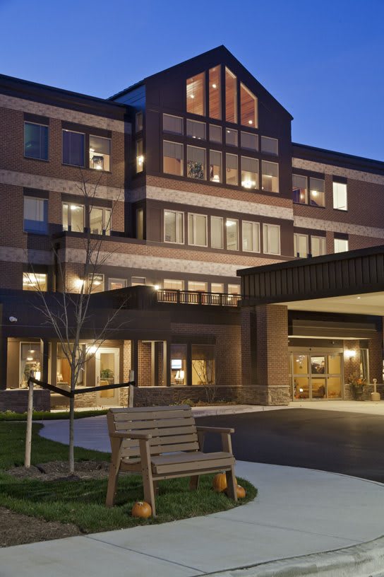 A well-lit building exterior in the evening with large windows and a welcoming entrance.