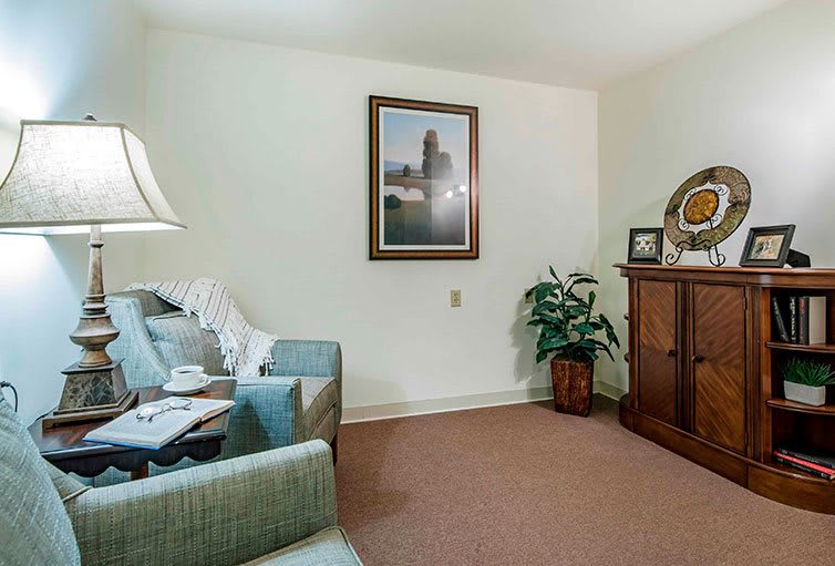 A cozy living room with a sofa, lamp, painting, and a potted plant.