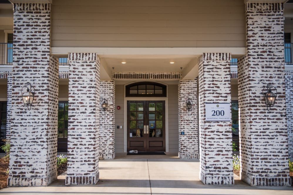 The entrance of a building with brick columns and a glass door.