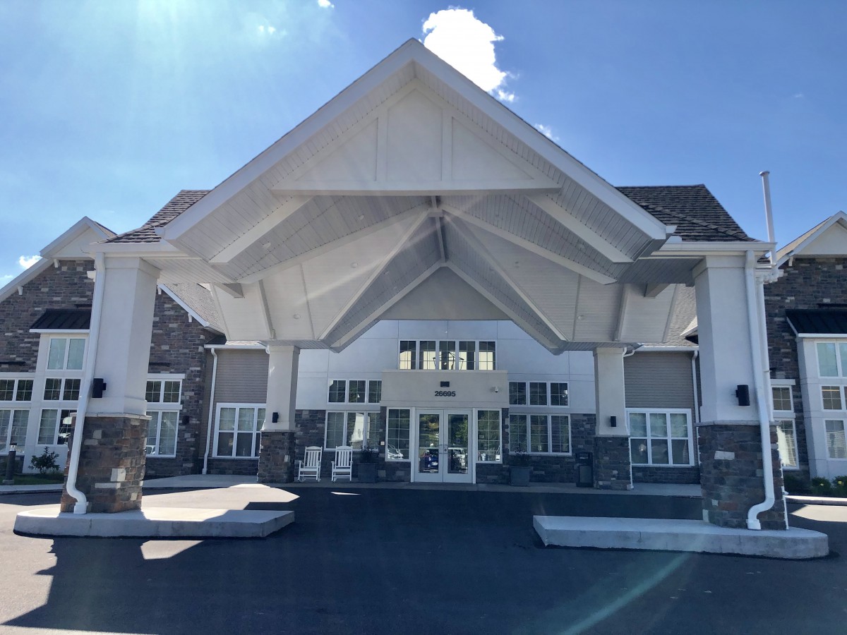 A modern building entrance with a prominent triangular roof design under a clear sky.