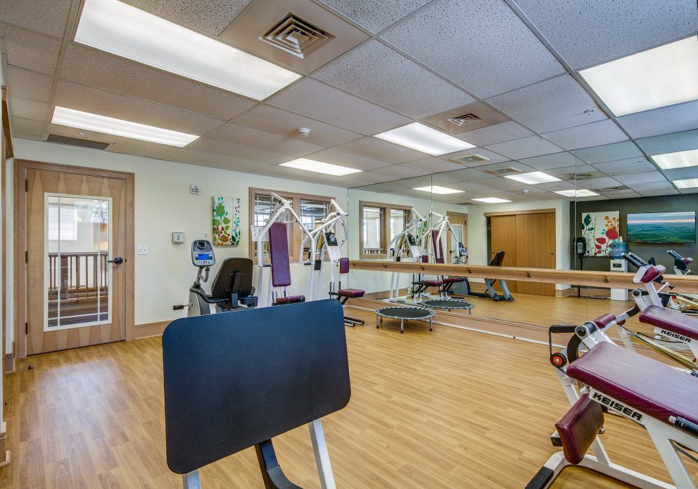A gym with various exercise equipment and mirrors on the walls.