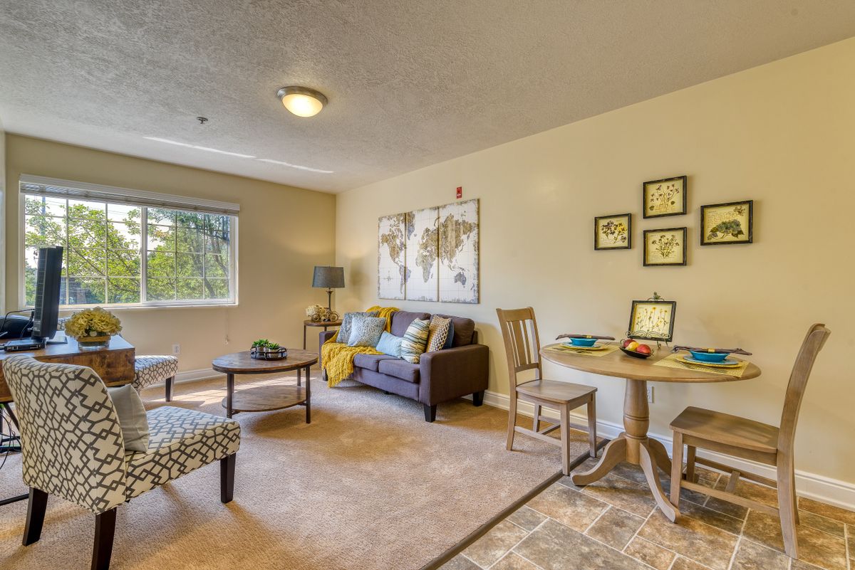 A cozy living room with a sofa, tables, and decorative artwork on the walls.