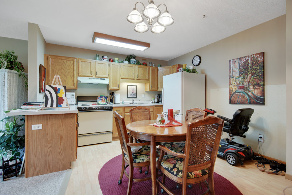 A cozy kitchen and dining area featuring wooden cabinets, a round table with chairs, and various appliances.