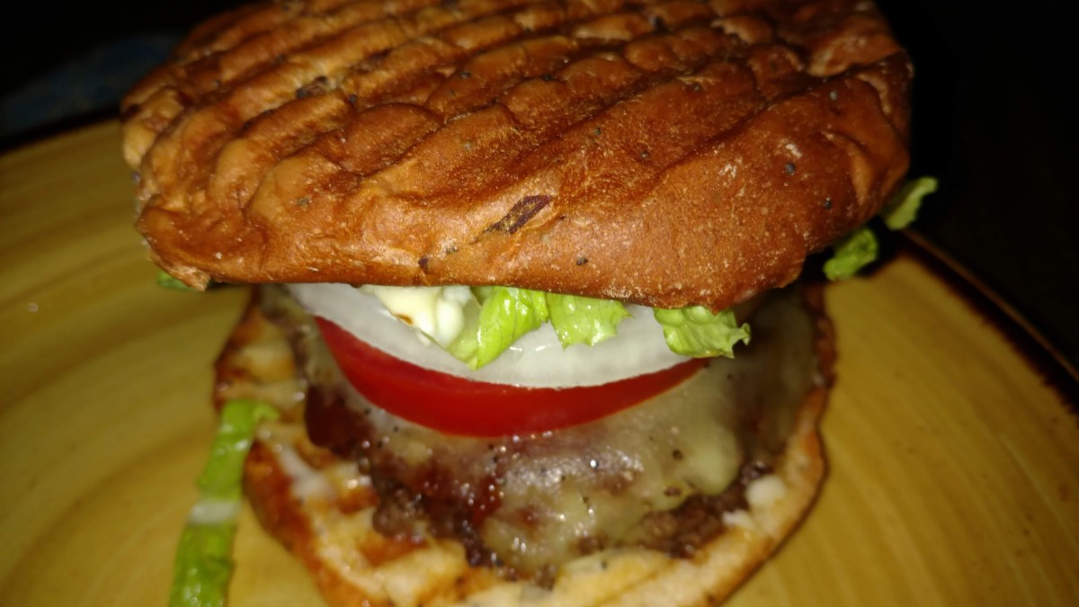 A delicious grilled burger with cheese, lettuce, tomato, and onion.