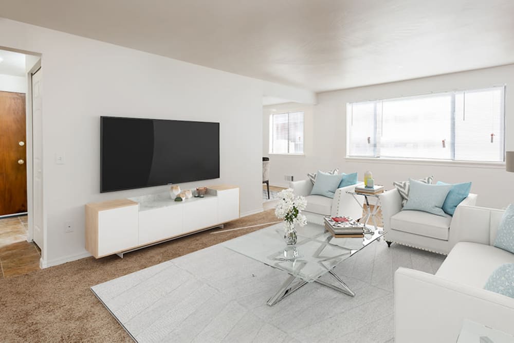A modern, minimalist living room with white furniture and a large television.