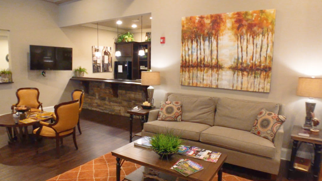A cozy living room with a sofa, artwork on the wall, and a coffee table topped with magazines and a plant.