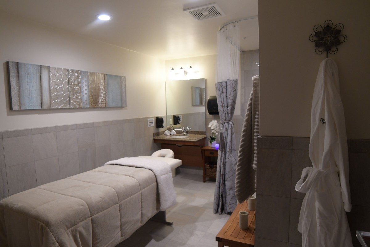 A serene massage room with a single bed, soft lighting, and calming decor.
