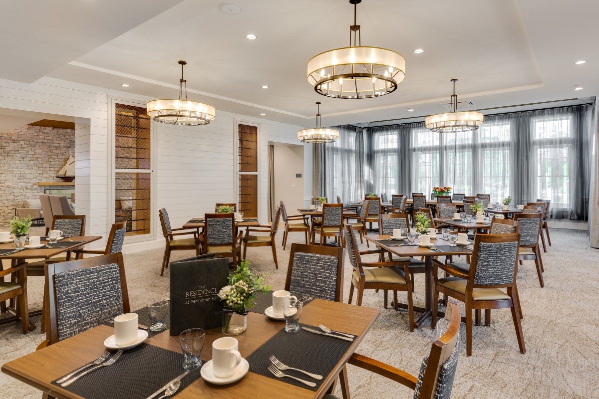 An elegant dining room with neatly arranged tables and chairs, complete with chandeliers and formal table settings.