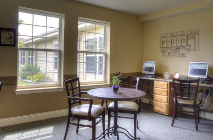 A cozy office space with a table, chairs, and a desk by the window.