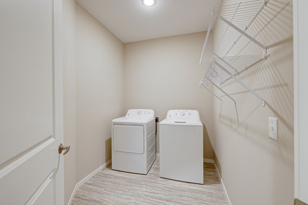 A compact laundry room featuring a washer and dryer set with shelving above.