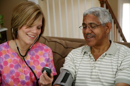 A healthcare professional checks a patient's blood pressure while they both smile.