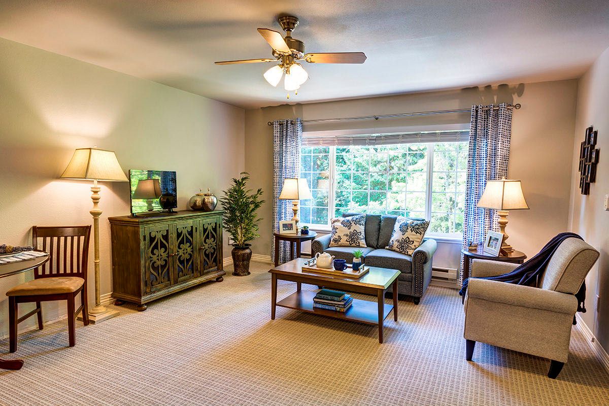 A cozy living room with a sofa, coffee table, and large window offering natural light.