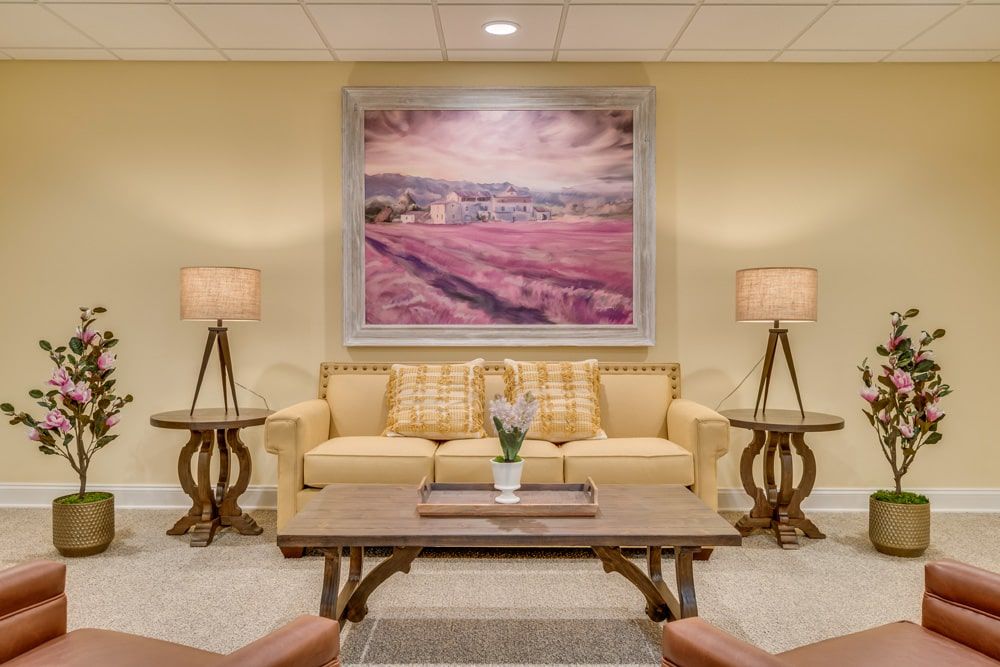 A cozy living room with a sofa, framed artwork, and matching lamps on either side.