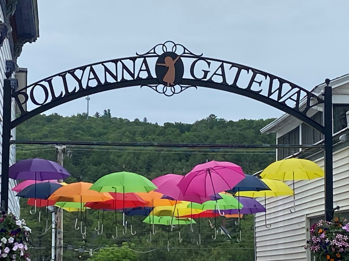 Colorful umbrellas hang beneath the gateway arch labeled 'POLLYANNA GATEWAY'.