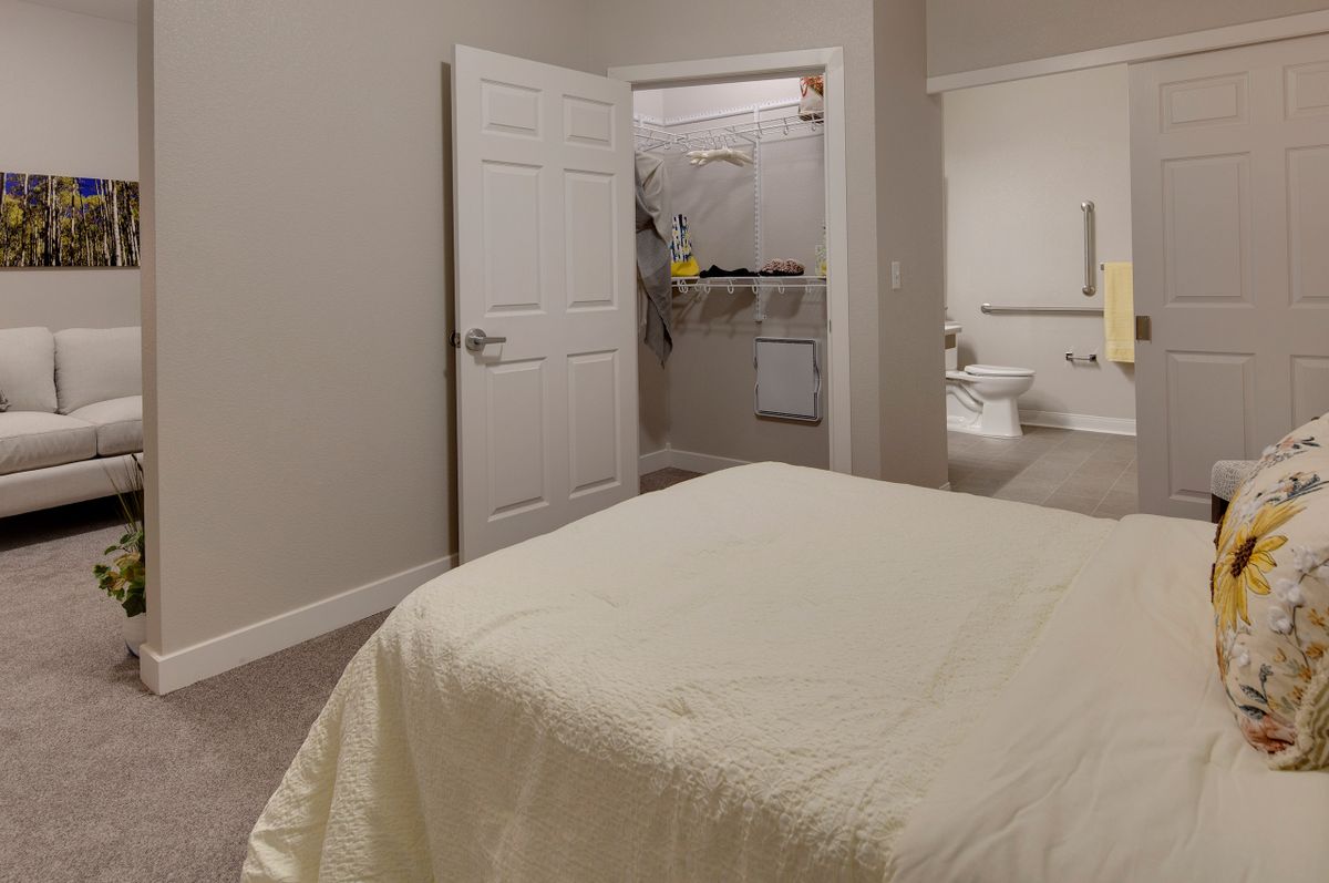 A cozy bedroom with an open closet door and a neatly made bed.