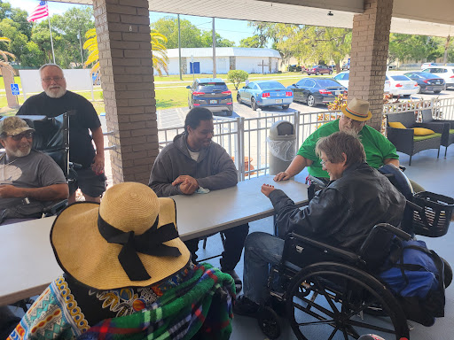 A group of people enjoying a social gathering outdoors, seated around a table.