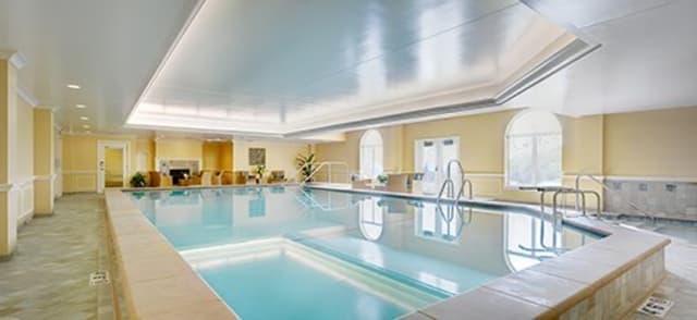 A serene indoor swimming pool area with seating and bright ambiance.