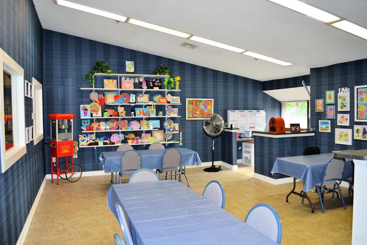 A colorful classroom featuring art supplies and bookshelves against blue walls.