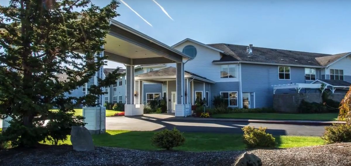 A large residential building with a covered entrance and landscaped surroundings.